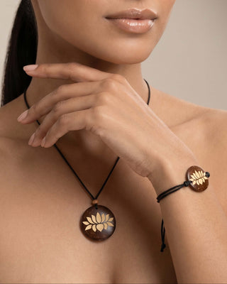 Woman wearing a wooden pendant necklace and bracelet on a neutral background