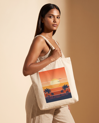 A woman wearing a beige dress holds a canvas tote bag with a retro sunset and palm tree graphic. The background is a solid warm beige studio backdrop.